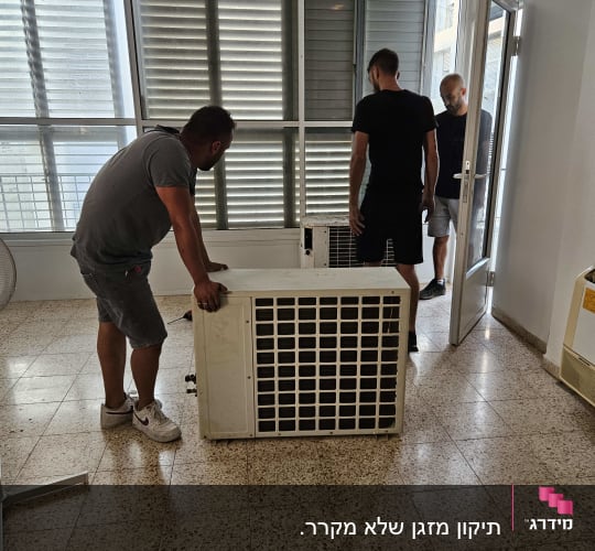 שלושה אנשים מזיזים יחידת מזגן בחדר